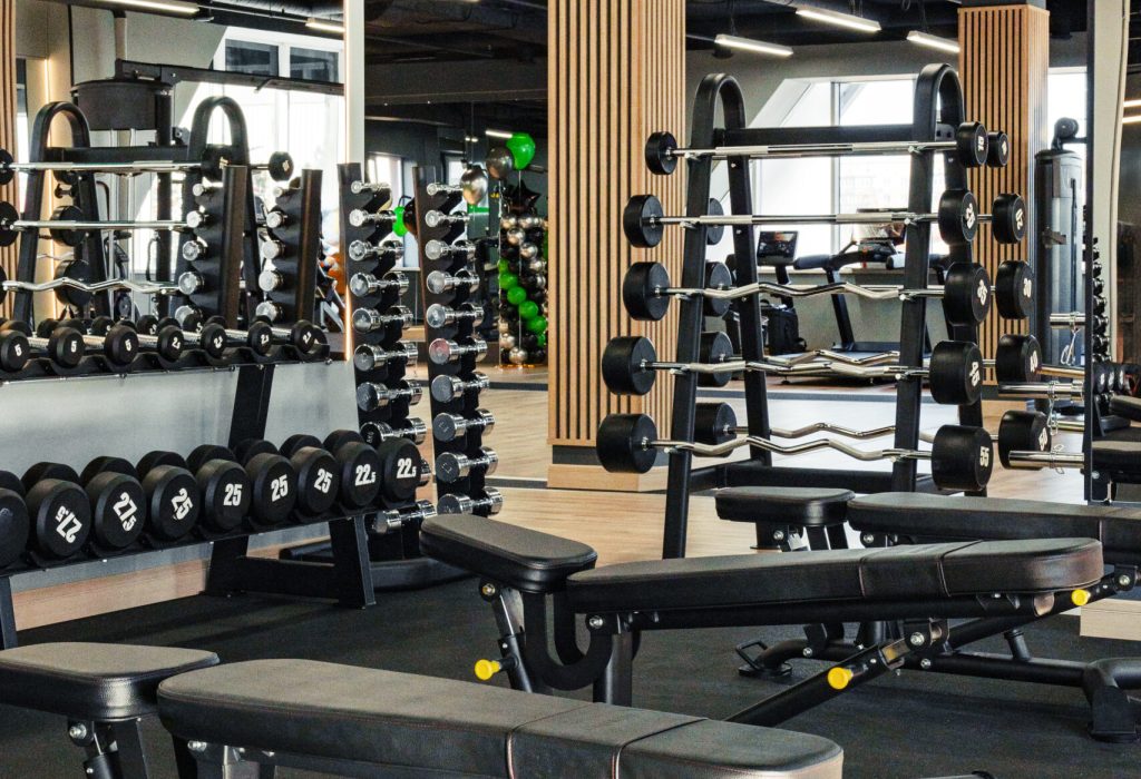 Spacious fitness center featuring workout benches and dumbbell racks for training.